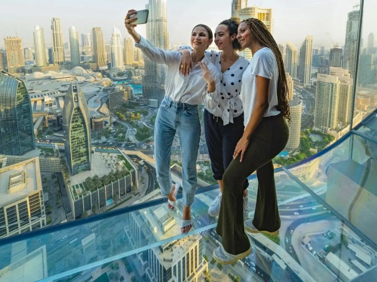 Visitors posing for a photo on the glass floor at Sky Views Observatory in Dubai